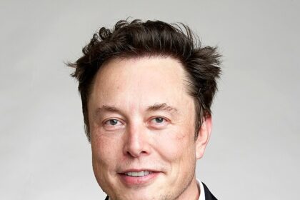 Elon Musk, CEO of Tesla and SpaceX, wearing a suit and smiling, representing his influence in technology, business, and innovation