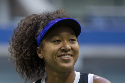 Naomi Osaka smiling during a tennis match, showcasing her confidence and sportsmanship