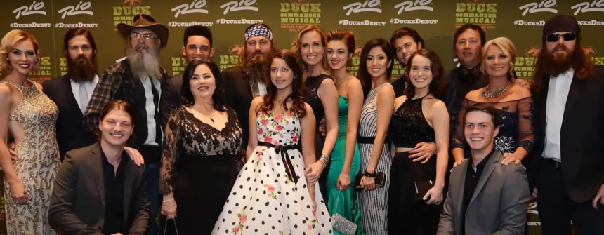 The cast of Duck Dynasty poses for a group photo at an event, showcasing their iconic styles and smiles.