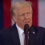 Donald Trump speaking at a public event, addressing an audience with a serious expression.