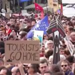 Protesters with signs advocating for tourism control in Spain, addressing housing and local community concerns