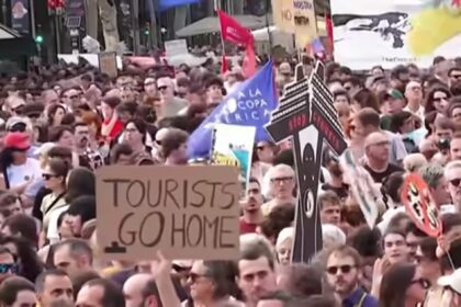 Protesters with signs advocating for tourism control in Spain, addressing housing and local community concerns