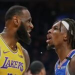 A live-action basketball game between the Los Angeles Lakers and the Philadelphia 76ers, capturing an intense moment on the court with players in motion