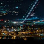 Night aerial view of a plane flying over a city, representing aviation, air traffic safety, and modern air travel.