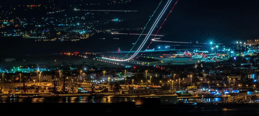 Night aerial view of a plane flying over a city, representing aviation, air traffic safety, and modern air travel.