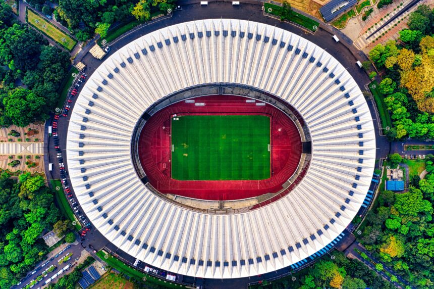 Aerial view of a stadium showcasing its vibrant green pitch surrounded by seating areas, symbolizing the grandeur of sporting events.