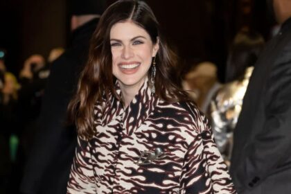 Alexandra Daddario at a public event, smiling and posing for the cameras.