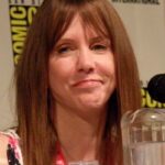 Laraine Newman at a public event, speaking into a microphone and smiling.