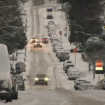 Snow-covered roads with cars driving cautiously amid icy weather conditions.