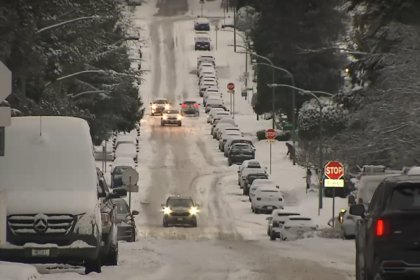 Snow-covered roads with cars driving cautiously amid icy weather conditions.