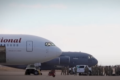 Airplane on the runway with a background of sky and other aircraft.