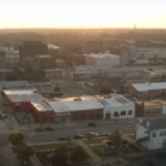 Aerial view of a cityscape with urban buildings and streets under clear skies, representing the latest news and developments in the region.