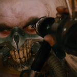 Immortan Joe from Mad Max: Fury Road, wearing his iconic breathing mask in the middle of a high-octane desert chase scene.