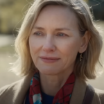 Naomi Watts smiling outdoors in a scarf, captured in a candid moment.