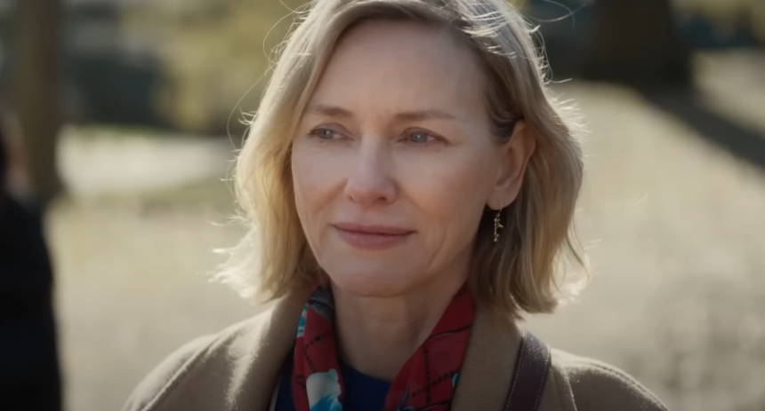 Naomi Watts smiling outdoors in a scarf, captured in a candid moment.