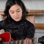 Female musician playing a guitar at Summerfest 2023.