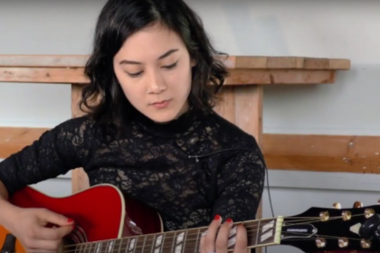 Female musician playing a guitar at Summerfest 2023.