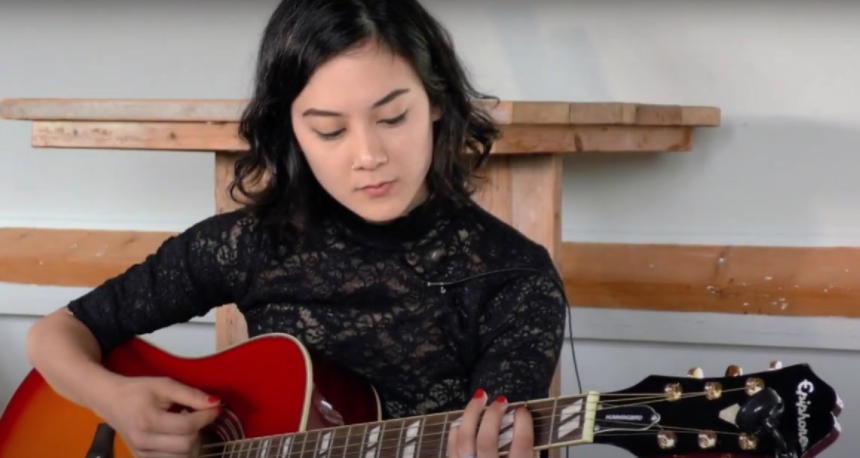 Female musician playing a guitar at Summerfest 2023.