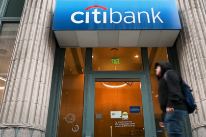 Citibank branch entrance with logo displayed above the glass doors, reflecting an urban street view.