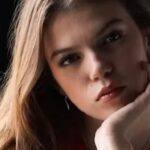 Close-up portrait of a young woman with a thoughtful expression, looking slightly away from the camera.