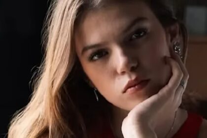 Close-up portrait of a young woman with a thoughtful expression, looking slightly away from the camera.