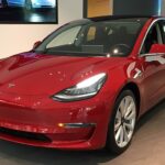 A red Tesla Model 3 on display at a showroom, representing the latest advancements, price changes, and autonomous driving technology in Tesla's 2025 lineup.