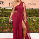 Laverne Cox wearing a long, vibrant red gown on the red carpet