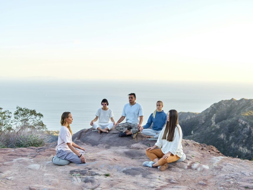 A group of people meditating together on a scenic hilltop during sunrise, embracing mindfulness and holistic wellness.